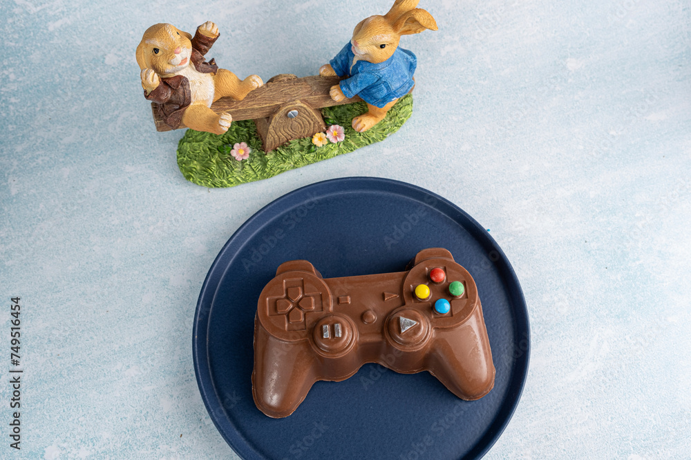 Wall mural milk chocolate in the shape of a video game controller alongside small rabbits_2.