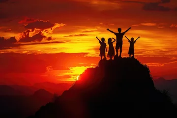 Fototapeten a family of people standing on top of a mountain at sunset © panu101