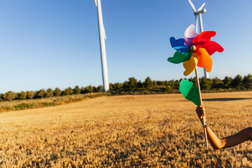 Person holding colorful pinwheel under a bright blue sky.