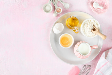 Fototapeta na wymiar Baking ingredients and kitchen utensils on a pink background, top view.