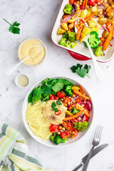 Baked vegetables with hummus bowl. Salad with baked potato, zucchini, broccoli and hummus.