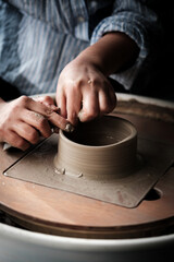 Fototapeta na wymiar Unrecognizable Ceramics Maker working with Pottery Wheel in Cozy Workshop Makes a Future Vase or Mug, Creative People Handcraft Pottery Class