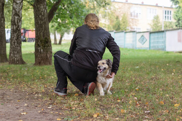 Naklejka na ściany i meble Man and dog walking in autumn park