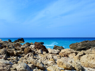 Fototapeta na wymiar View of splashing white waves in beach rocks and cliffs. Turquoise azure, tropical sea water