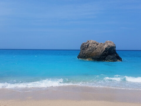 View of splashing white waves in beach rocks and cliffs. Turquoise azure, tropical sea water
