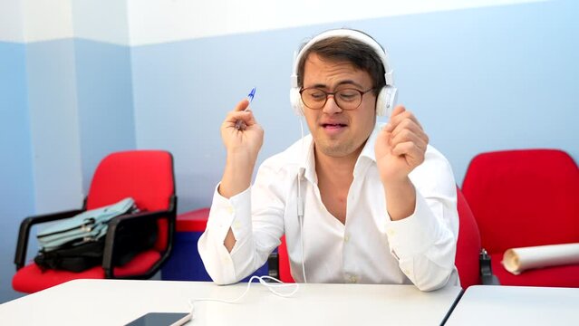 Man with down syndrome dancing sitting while listening to music using headphones and mobile