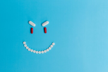 An evil smiling smiley face made of pills on a blue background