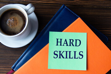 HARD SKILLS - words on a green sheet of paper against the background of colorful notepads and a cup of coffee.