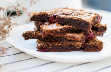 A little stacks of tasty sweet brownie with cherry on light background. Piece of cake.