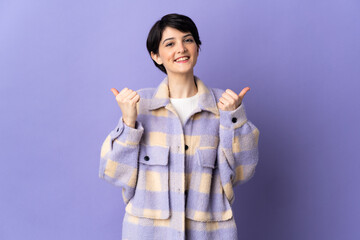 Woman with short hair isolated on purple background with thumbs up gesture and smiling