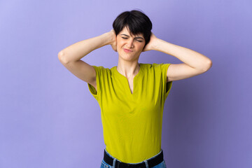 Woman with short hair isolated on purple background frustrated and covering ears