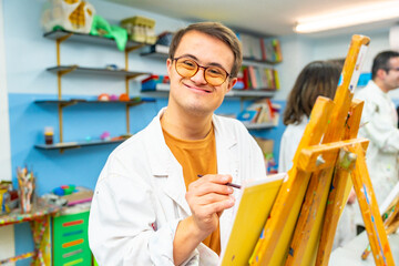 Man with down syndrome smiling at camera during painting class
