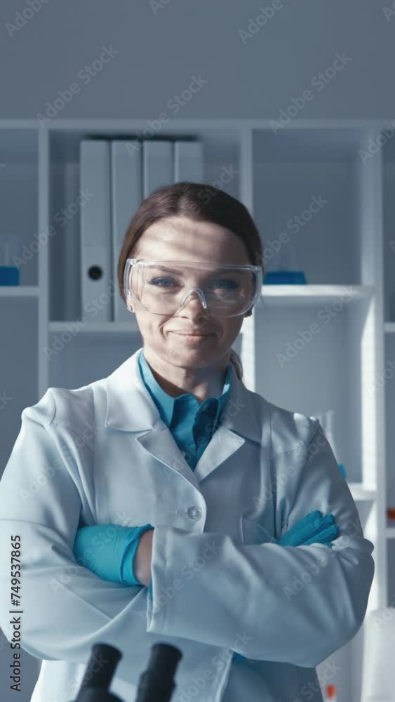 Poster Scientist woman in science lab posing and looking at camera Vertical video research in the laboratory: a scientist is studying new methods of combating diseases.