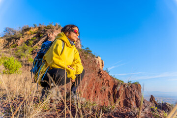 woman in the mountains, with backpack and a yellow jacket, motivated by exploring new places....
