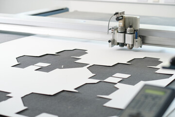 A laser cutting machine cutting out intricate design templates in a white clinical manufacture...