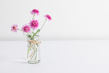 Pink flowers in transparent vase on table on white wall background. Valentine's Day, Happy Woman's Day, Mother's Day, Birthday, Wedding