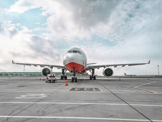 A large plane stands on the runway at Istanbul airport in the morning on a cloudy day, Turkey. Front view of a lonely red and white airplane at the airport