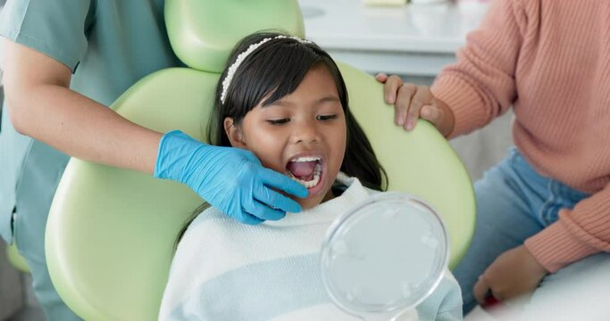 Child, dentist or examination of teeth in surgery, trust or patient by doctor for oral hygiene. Girl, parent or support in consultation by tooth professional or mirror for interactive dental checkup