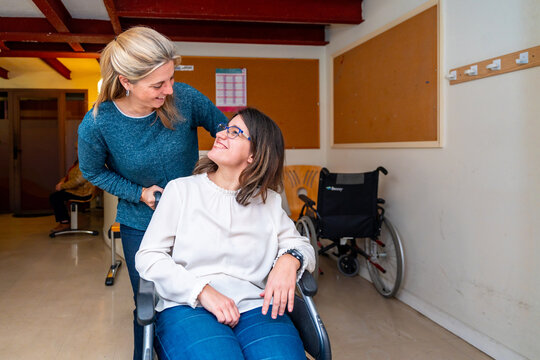 Caregiver pushing the wheelchair of a disabled woman