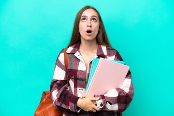 Young student caucasian woman isolated on blue background looking up and with surprised expression