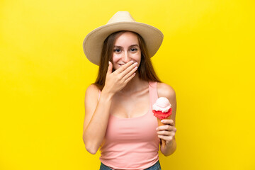 Young caucasian with a cornet ice cream isolated on yellow background happy and smiling covering mouth with hand