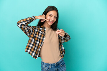 Young French woman isolated on blue background making phone gesture and pointing front