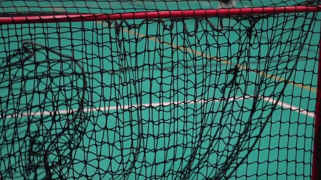 Floorball ball hits the net in slow motion