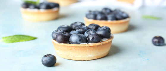 Tasty tartlet with blueberries on blue background