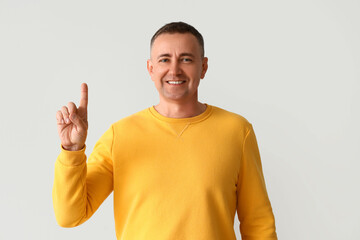 Mature man pointing at something on light background