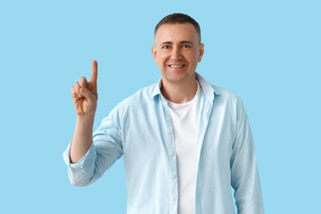 Mature man pointing at something on blue background