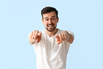 Handsome man pointing at viewer on blue background