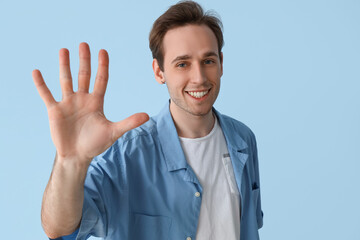 Young man showing hand on blue background, closeup