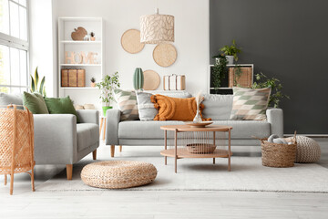 Interior of light living room with grey sofas, coffee table and wicker poufs - obrazy, fototapety, plakaty