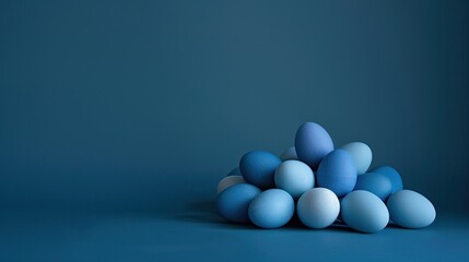 A collection of eggs painted in various shades of blue is grouped against a dark blue background.