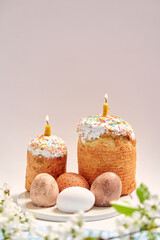 Two paski with burning candles and eggs on white background