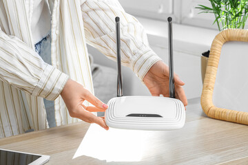 Woman with wi-fi router near shelf at home, closeup