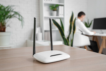 Modern wi-fi router on table in office, closeup