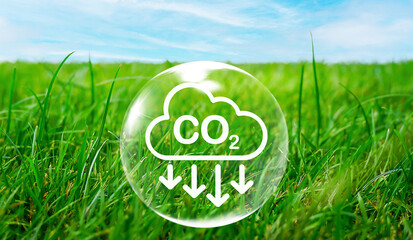 CO2 emission reduction icon inside of air bubble on green grass field in natural against blue sky...