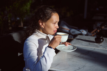 Portrait of a confident serious African American business woman enjoying her hot drink in the outdoor terrace of a cafe