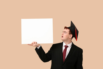 Male student in mortar board with blank poster on beige background