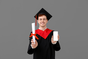 Male graduating student with mobile phone and diploma on grey background