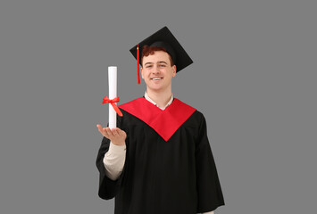 Male graduating student with diploma on grey background
