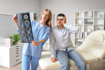 Female doctor and man with brain concussion examining MRI scan in clinic