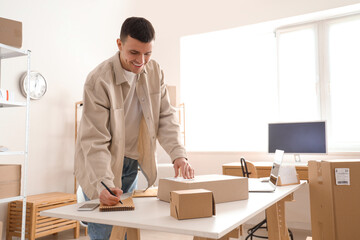 Male online store seller packing parcel for client in warehouse