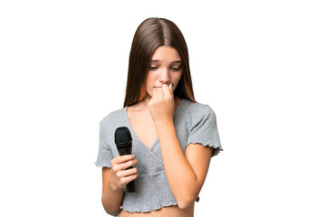 Teenager singer girl picking up a microphone over isolated background having doubts