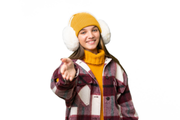 Teenager caucasian girl wearing winter muffs over isolated background shaking hands for closing a good deal