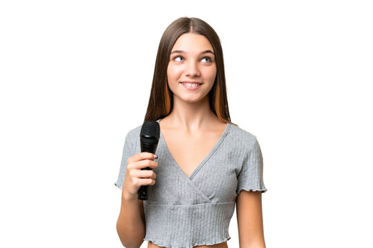 Teenager singer girl picking up a microphone over isolated background thinking an idea while looking up