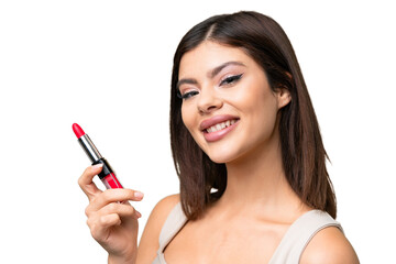 Young Russian woman with rainproof coat and umbrella over isolated chroma key background holding red lipstick