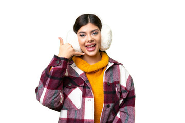 Young Russian woman wearing winter muffs over isolated chroma key background making phone gesture....
