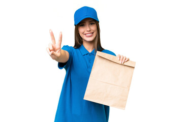 Young beautiful caucasian woman taking a bag of takeaway food over isolated background smiling and showing victory sign